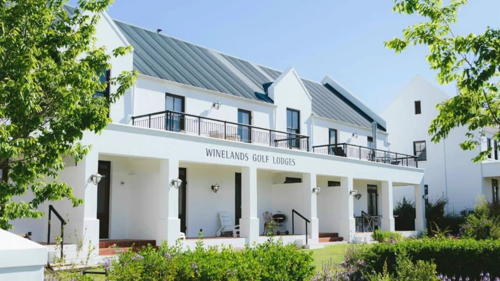 Exterior of Winelands Golf Lodges at De Zalze showing whitewashed Cape Dutch facade, private balconies and lush garden surrounds on the De Zalze Winelands Golf Estate, Stellenbosch